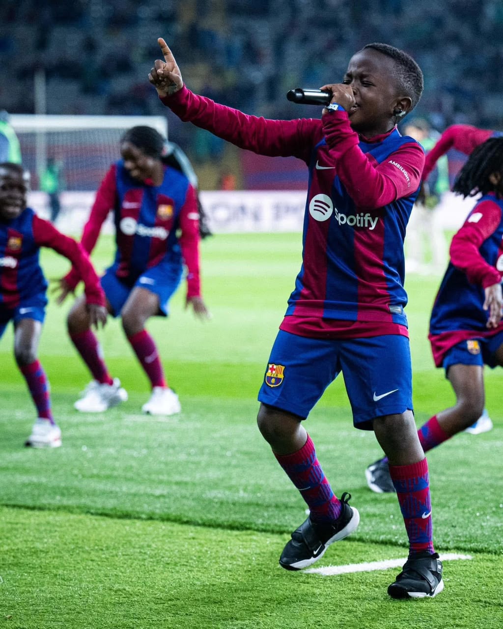 Prince performing with microphone in stadium wearing Barcelona kit